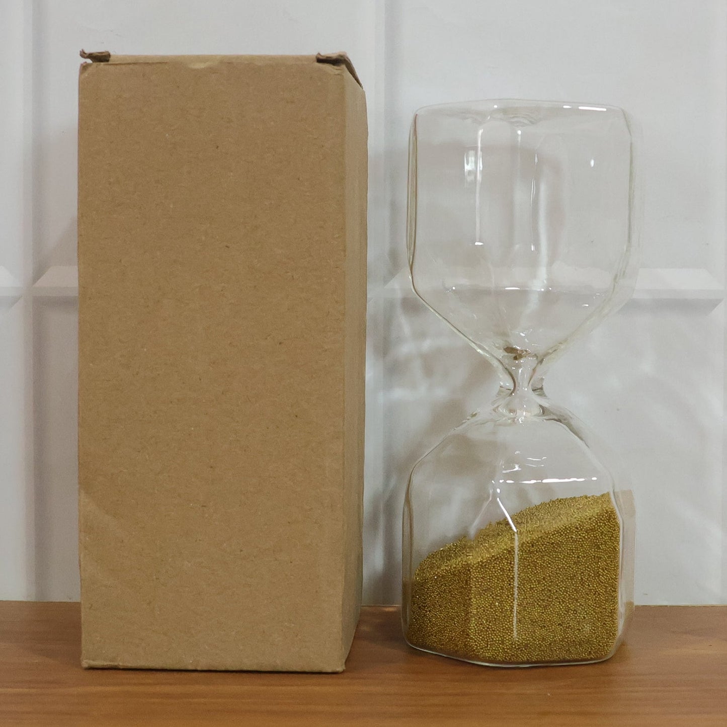 Clear glass 4-minute sand timer hourglass on a clean white background.