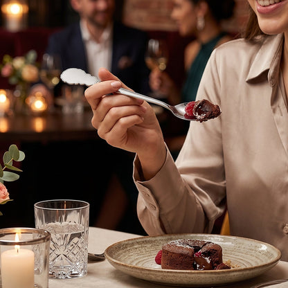 Stainless steel carved handle dinner spoon in use, scooping food during a meal.