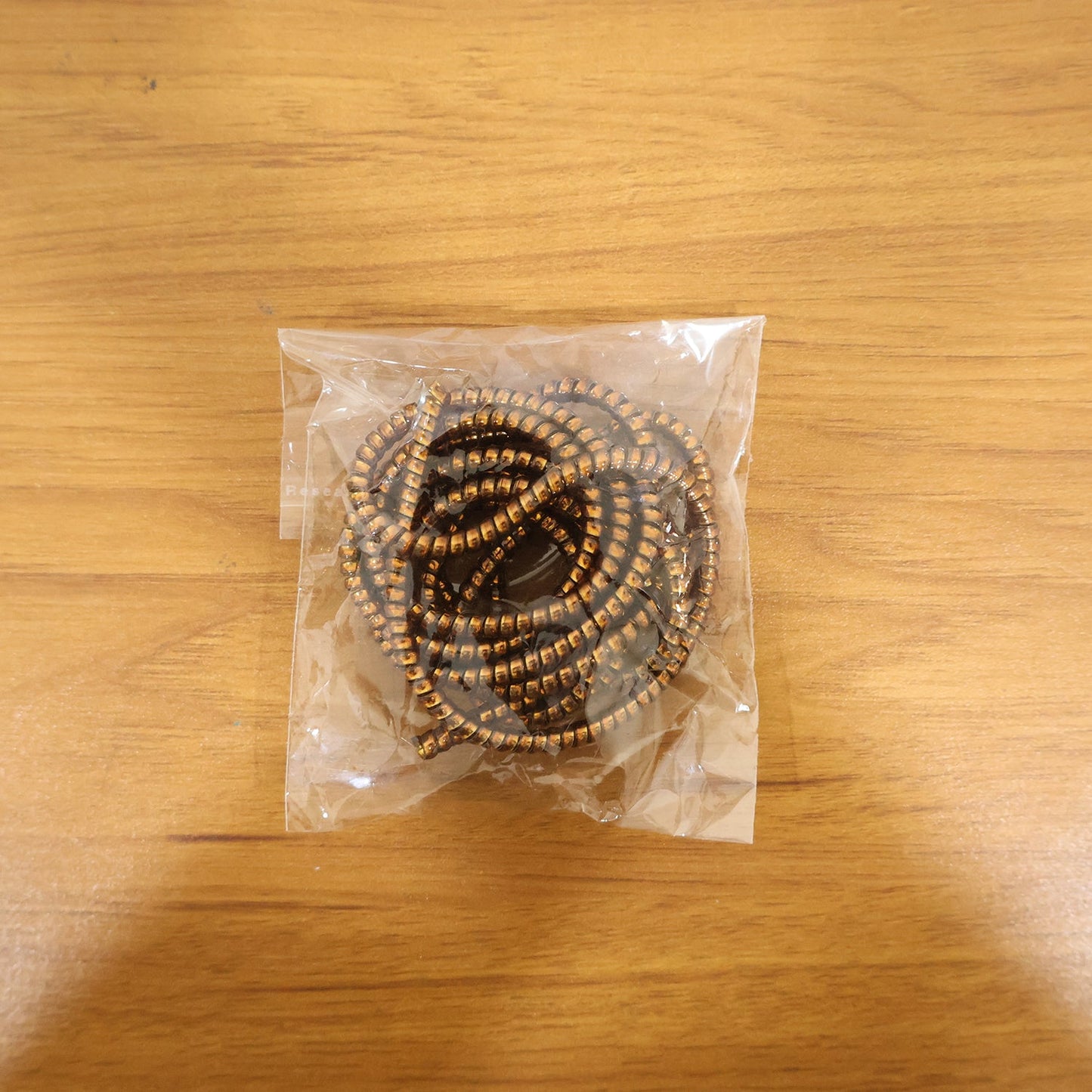 Spiral cable protector sleeve in use, neatly wrapping a cable on a desk.