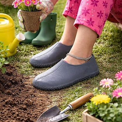 A person wearing dark gray silicone covers and pink floral pants sits in a garden with a watering can and trowel nearby.